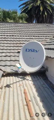 DStv satellite dish on tiled roof with palm trees
