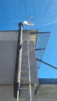 DStv satellite dish installation on roof with ladder