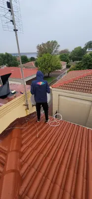Professional technician on roof installing satellite dish
